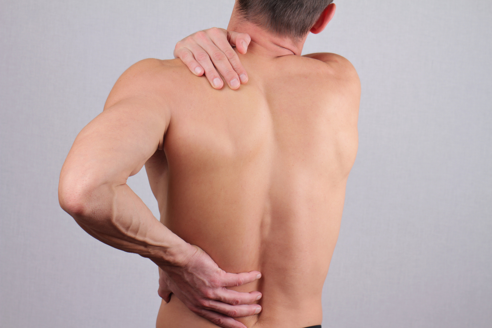 Man with neck and back pain. Man rubbing his painful back close up. Pain relief concept